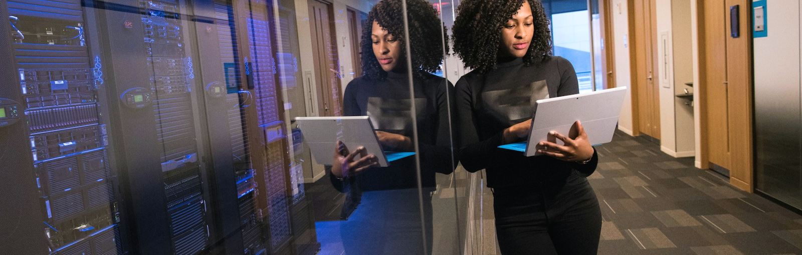 Professionnelle de l'informatique avec un ordinateur portable devant des baies de serveurs dans une salle d'hébergement