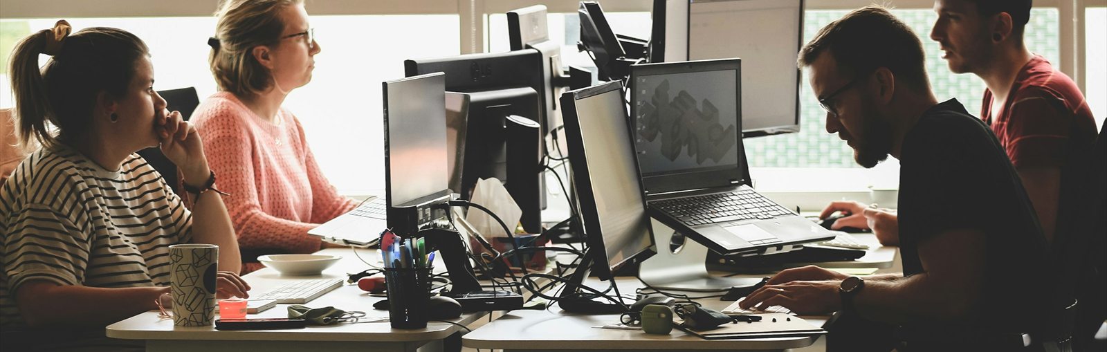 Collègues au travail devant leurs écrans et ordinateurs portables dans un bureau lumineux